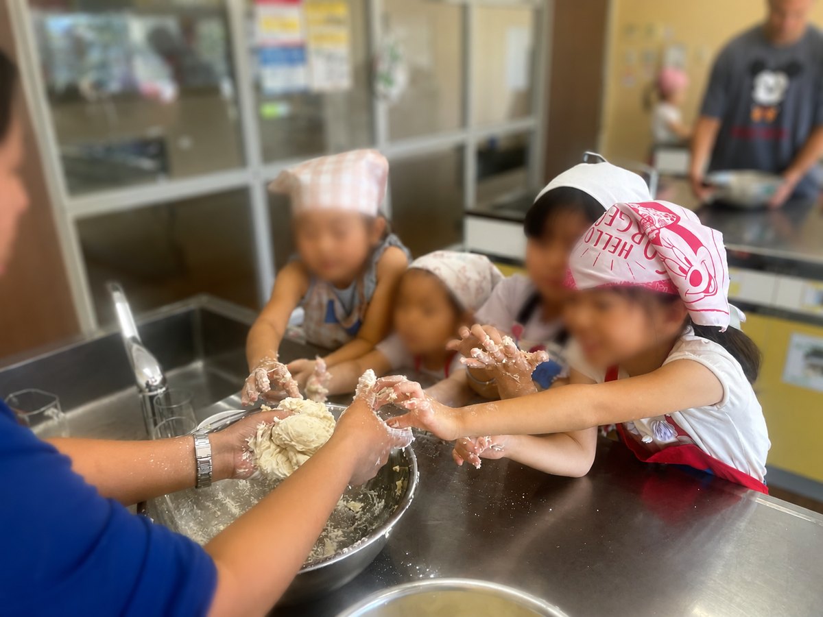 サマースクールの料理教室でパン生地をこねる子どもたち